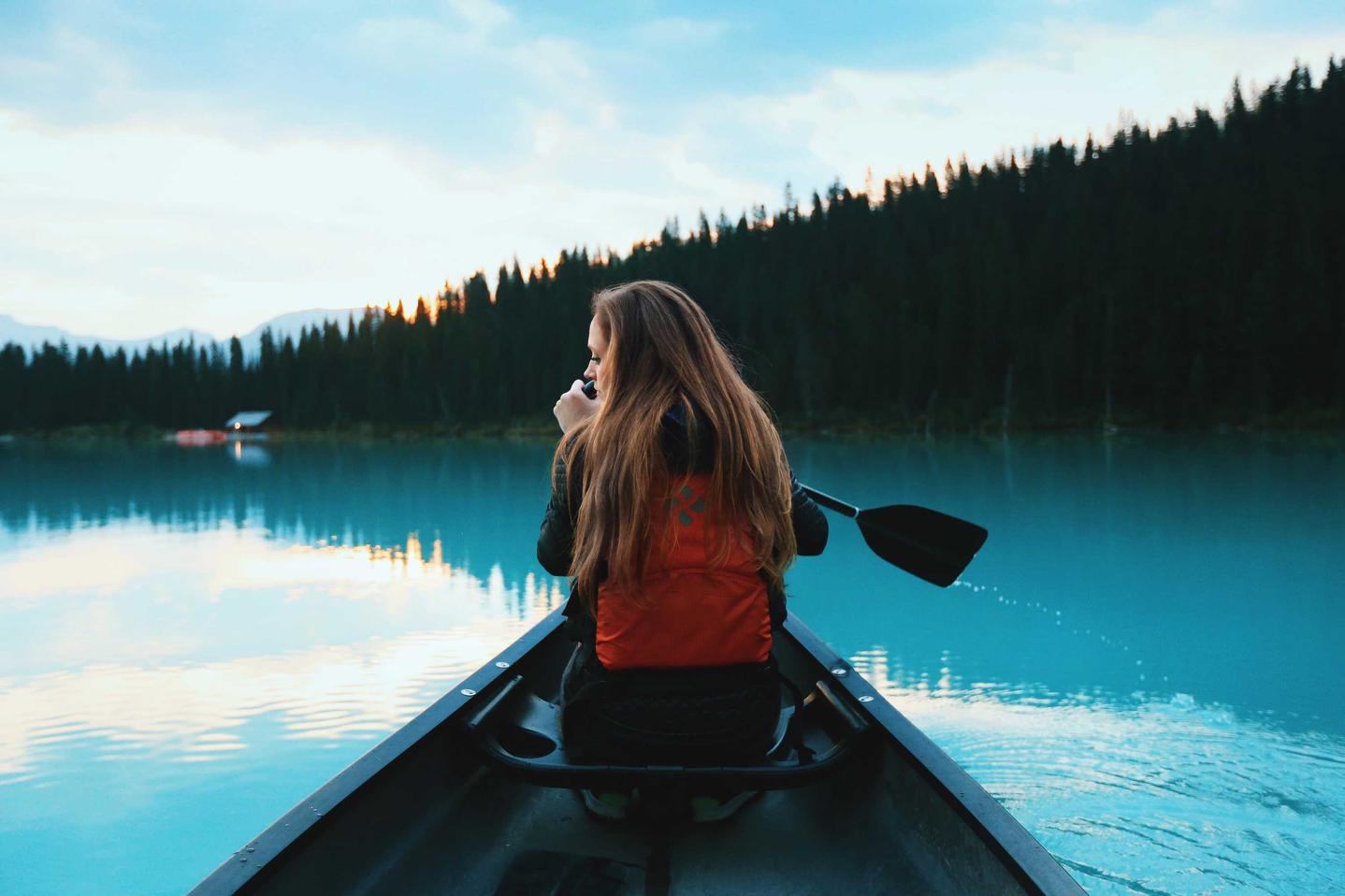 Woman paddling a canoe on a peaceful lake