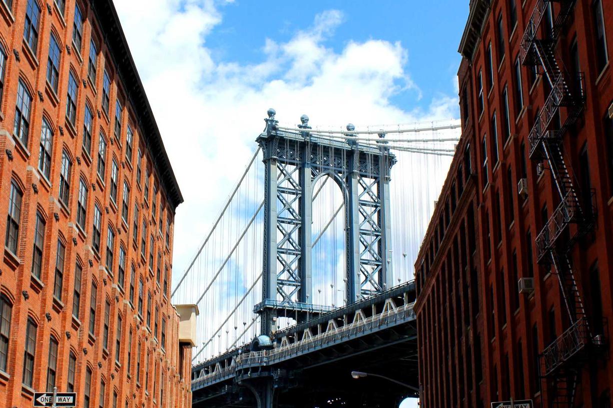 The Brooklyn Bridge with cables and towers between buildings.