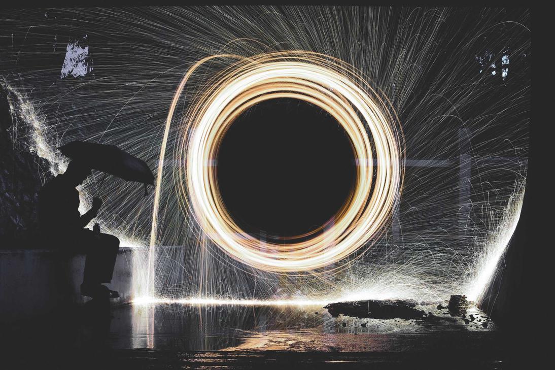 A man creates a circle of fire in a dark room. The image captures a moment of performance art.
