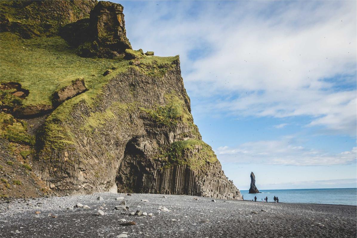 A scenic view of Reynisfjara Beach featuring distinctive rock formations and a pebbled shoreline.
