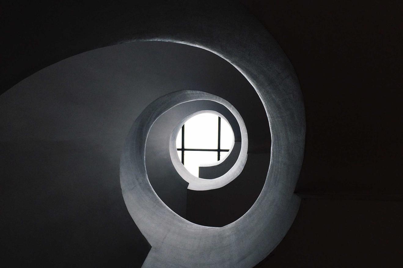 A spiral staircase with a window at the top. The window has a grid pattern.