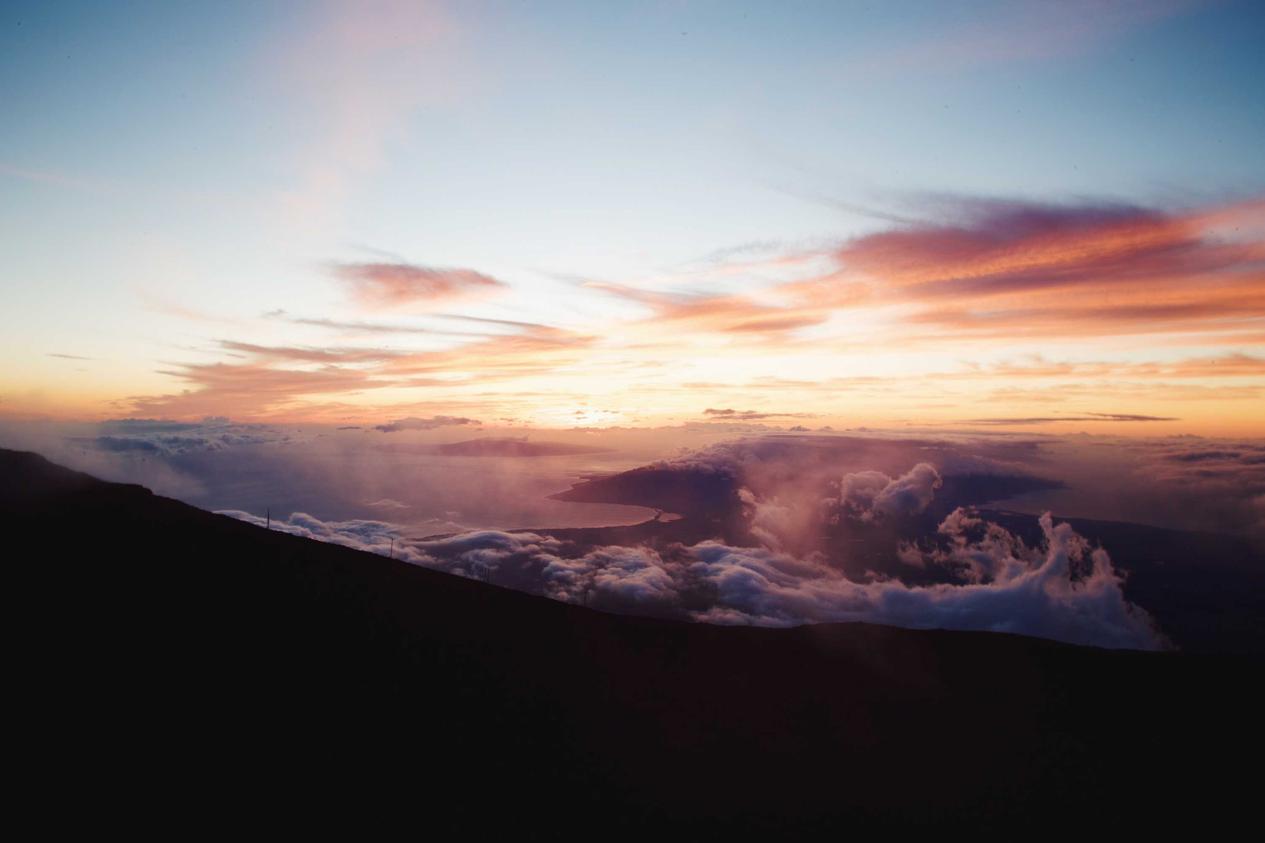 A breathtaking sunset over mountains with clouds. The sky is painted with hues of orange and pink.